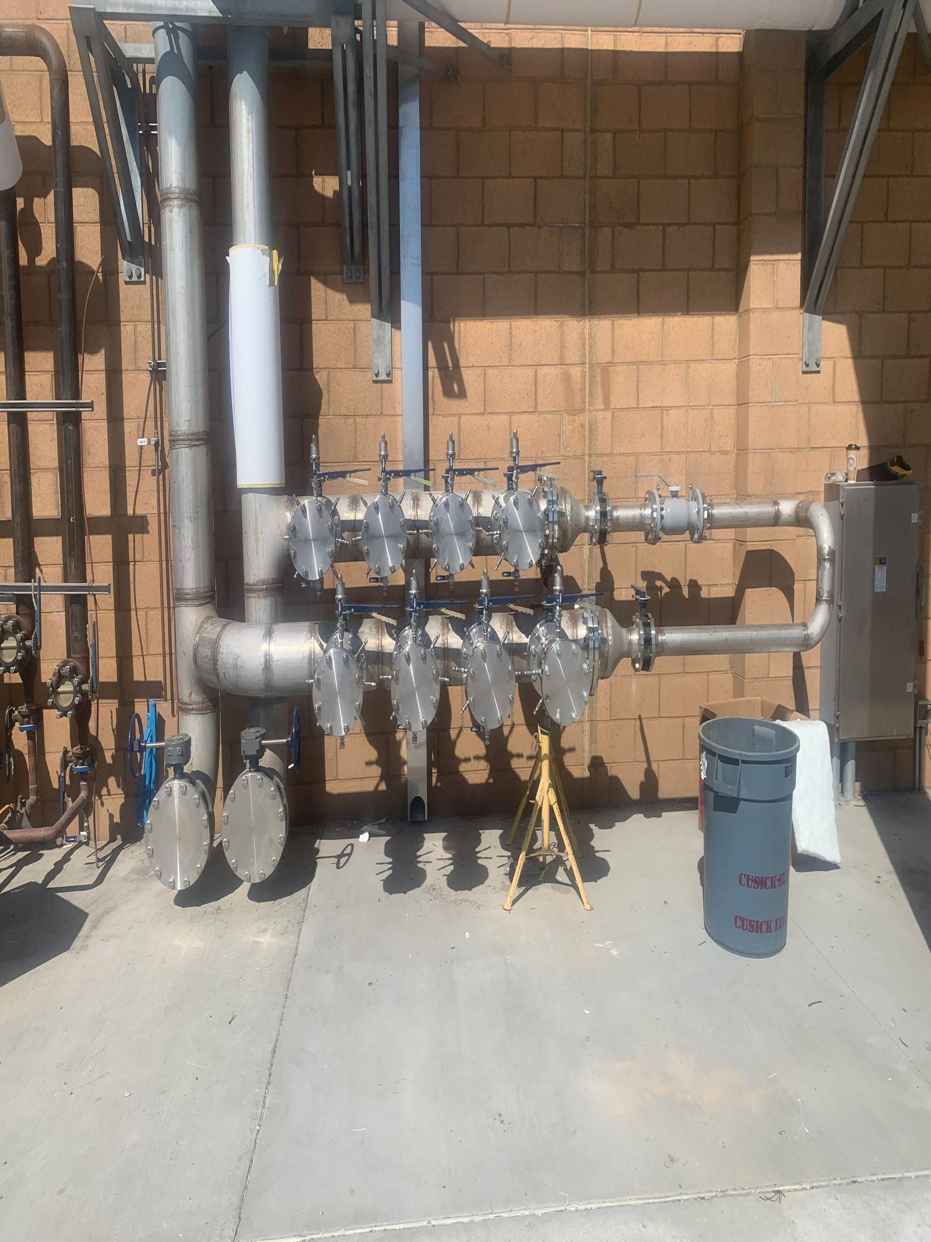 A bunch of pipes are lined up against a brick wall.