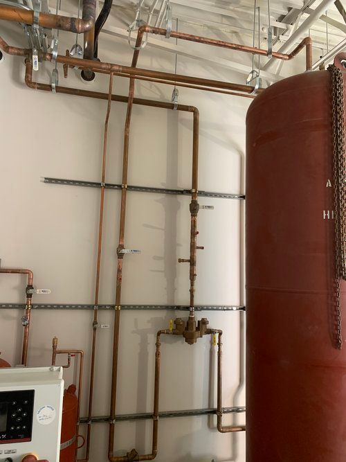 A room with copper pipes and a red tank