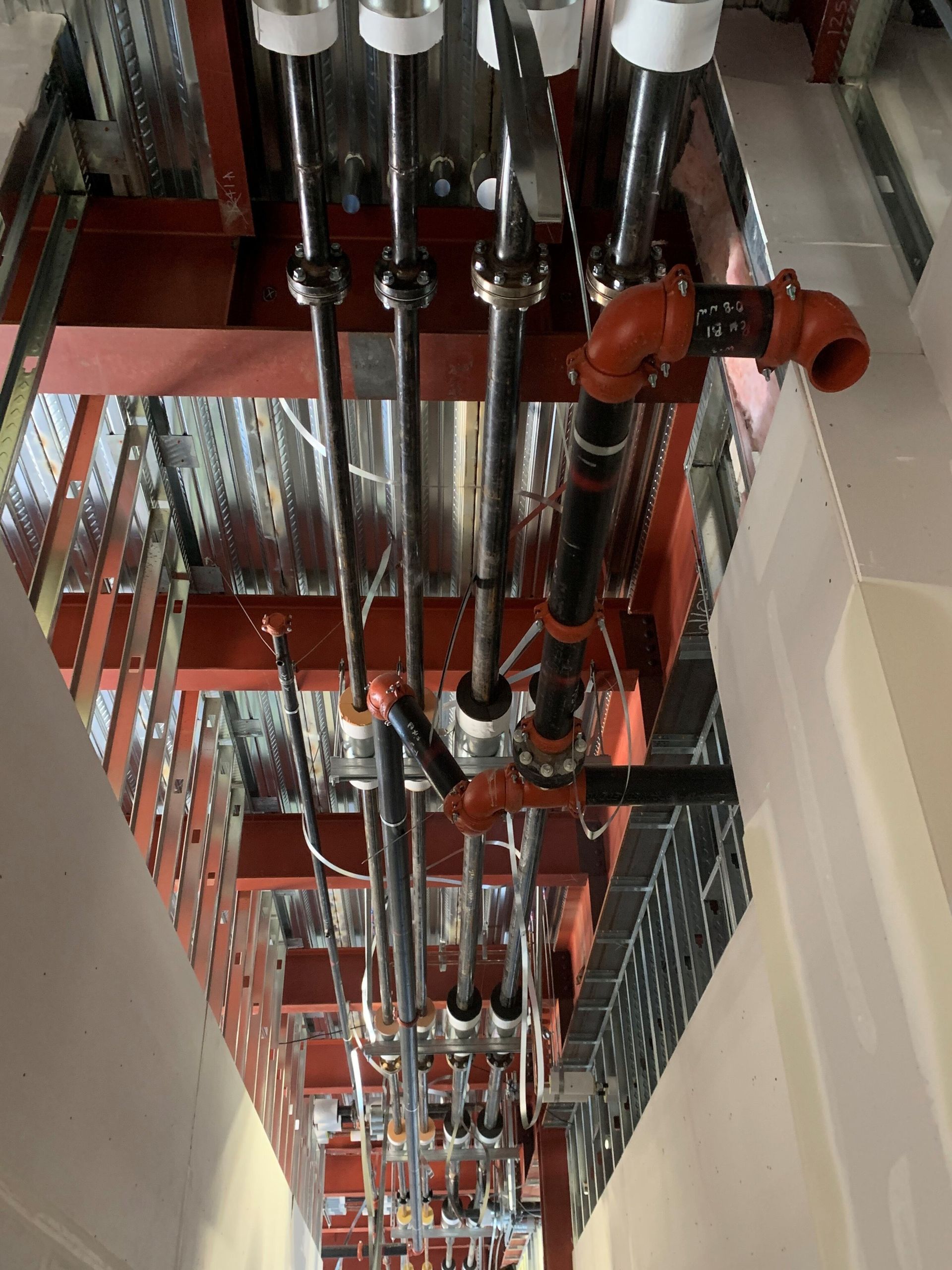 A bunch of pipes are hanging from the ceiling of a building.