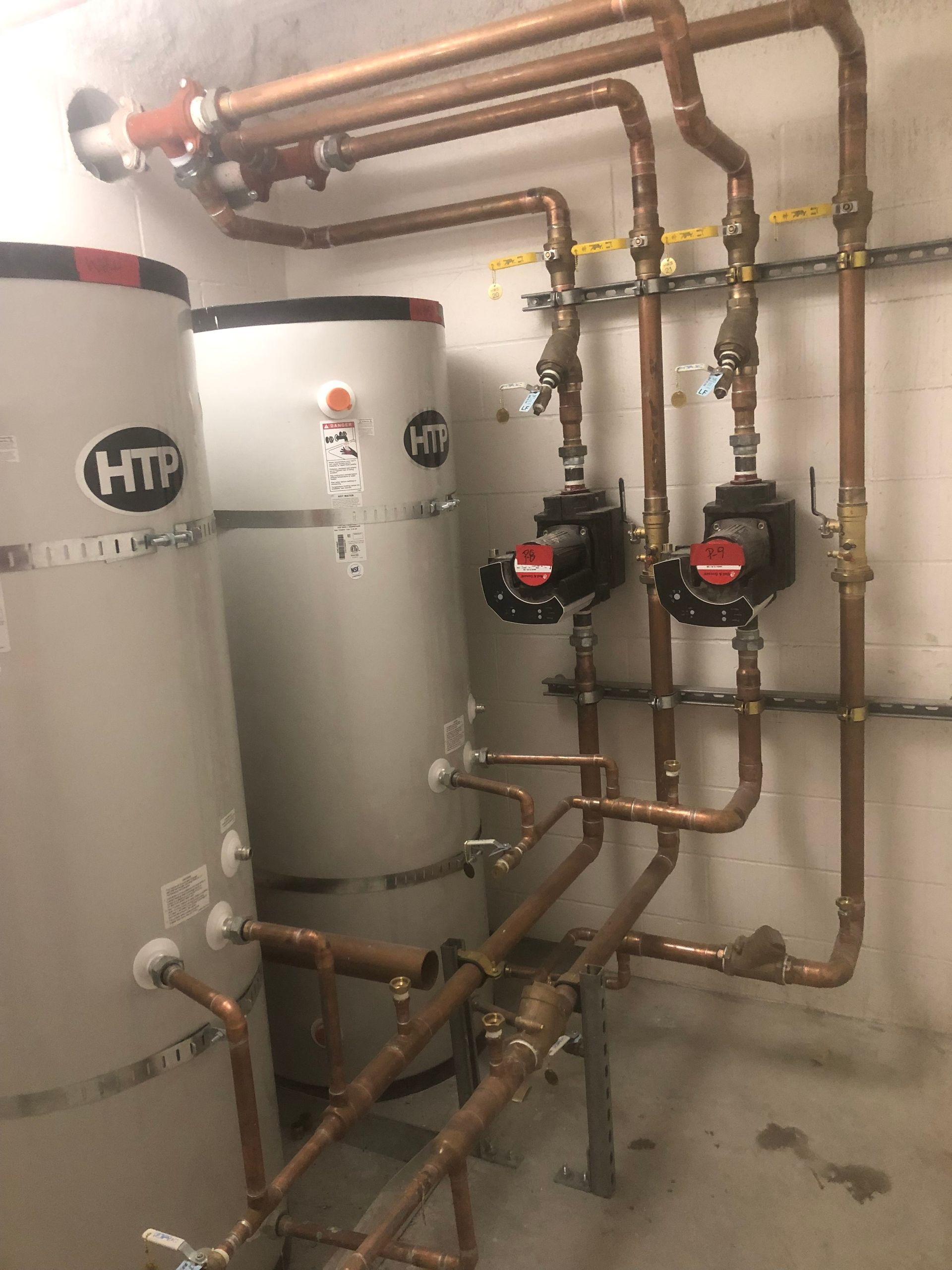 A room with a lot of pipes and a water heater.