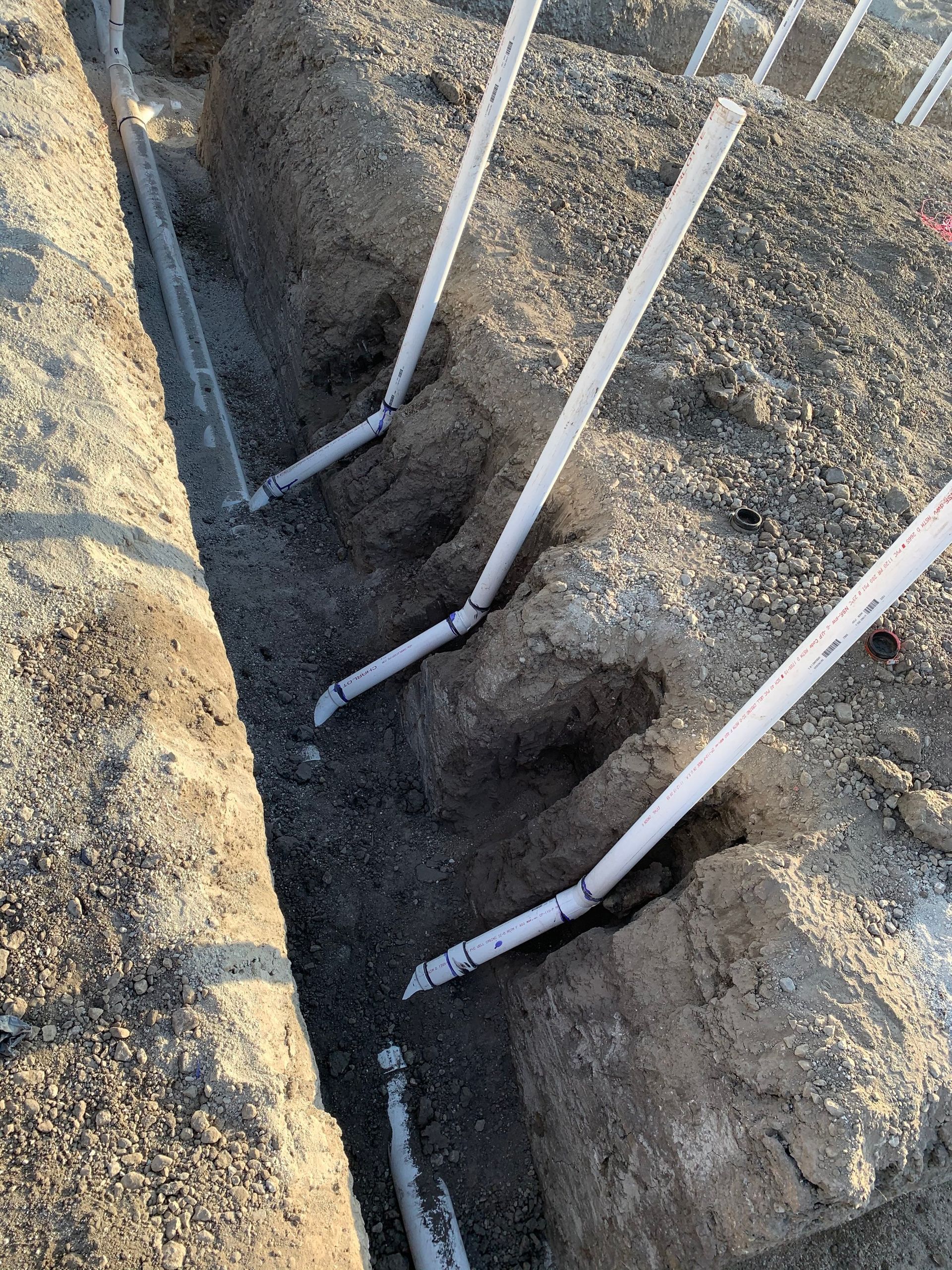 A bunch of pipes are laying in the dirt.