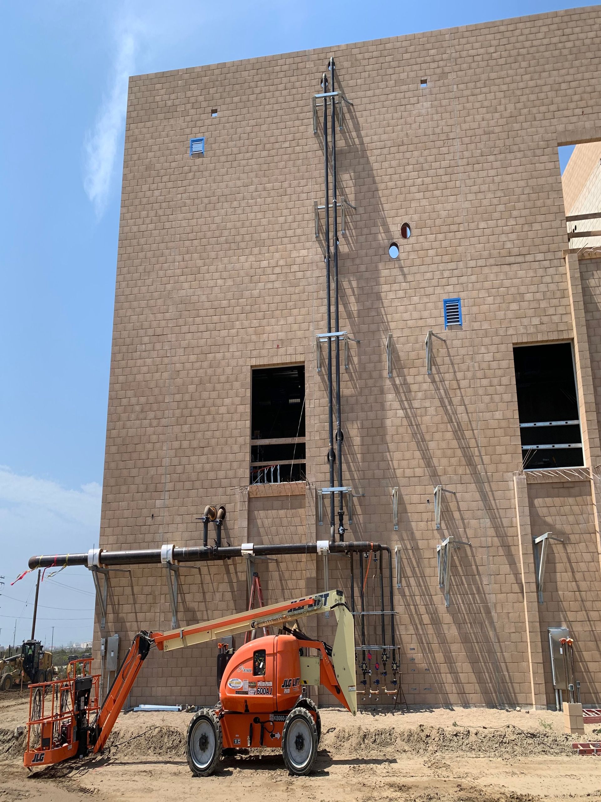 A construction vehicle is parked in front of a large brick building under construction.