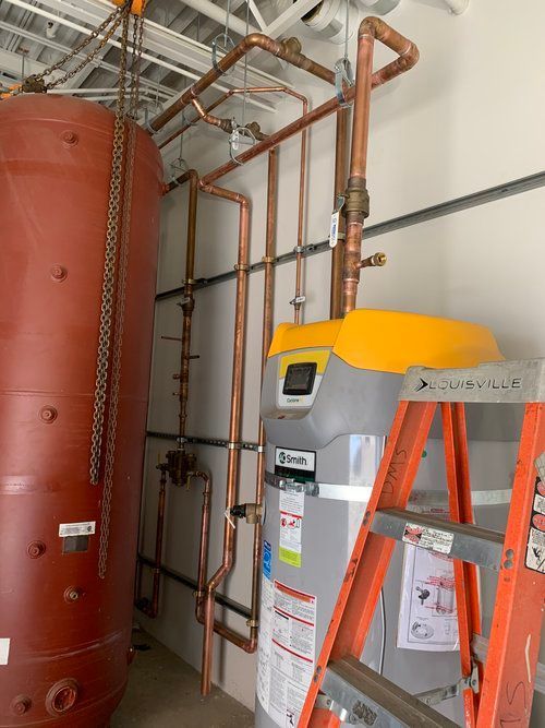 A ladder is sitting next to a water heater in a room.