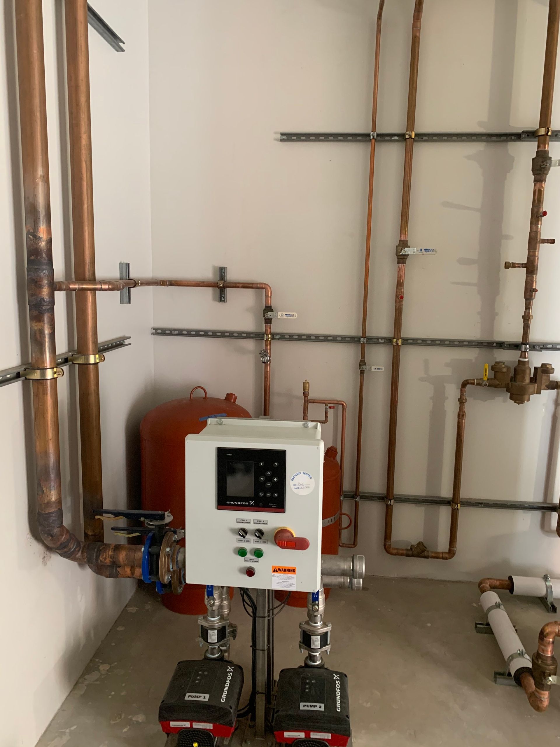 A room with copper pipes and a control panel