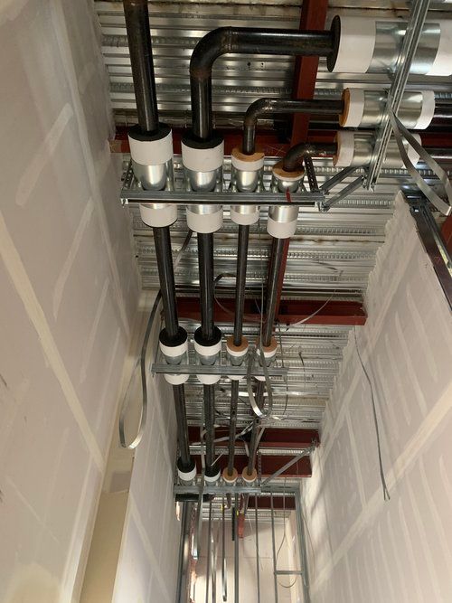 A bunch of pipes are hanging from the ceiling of a building.
