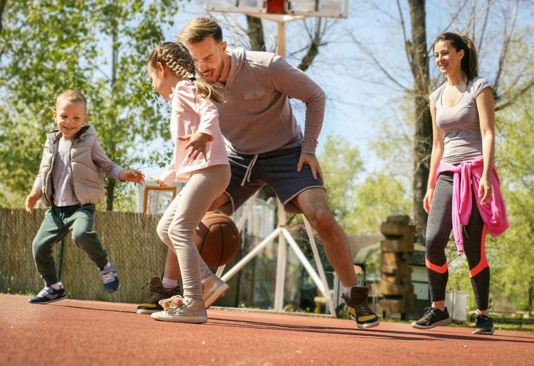 A family is playing basketball on a court.