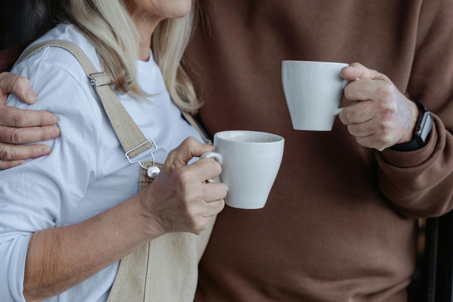 A man and a woman are holding two cups of coffee.