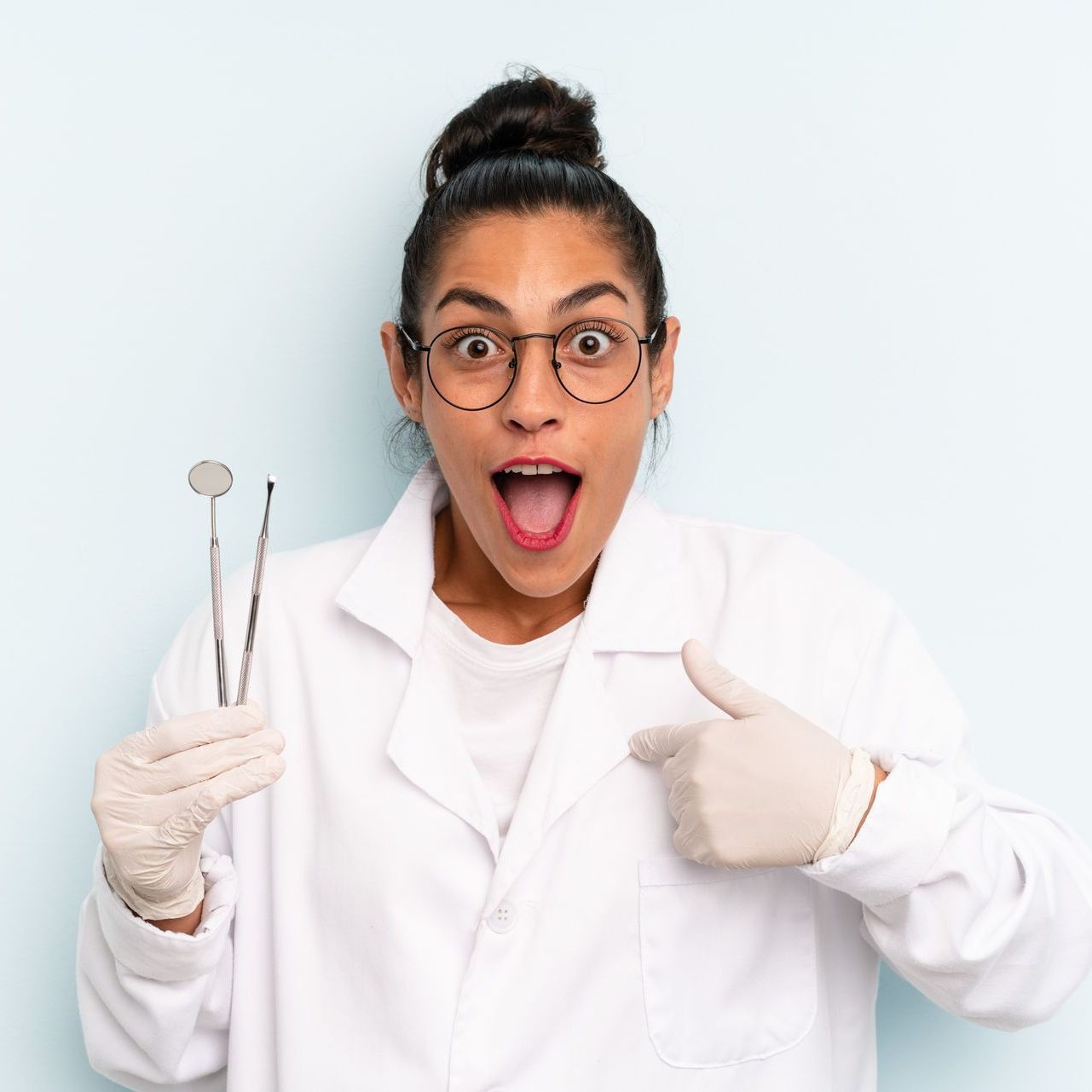 Dental assistant excited and pointing to herself while holding dental instruments.