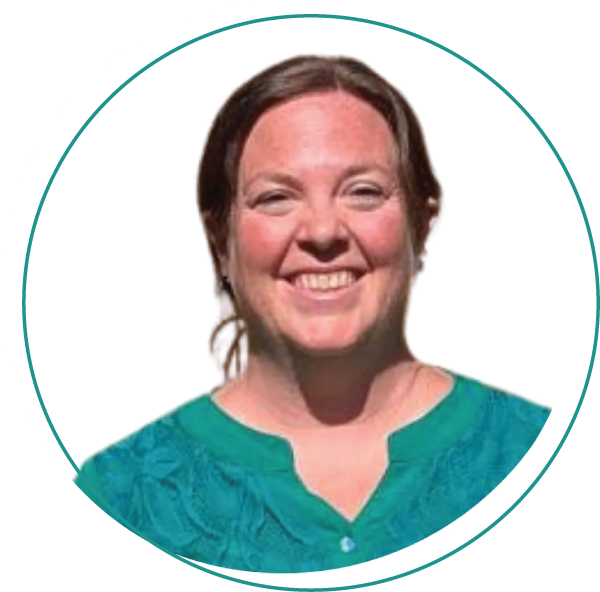 Smiling woman with short blonde hair, wearing a blue-green shirt and layered necklace, outdoors.