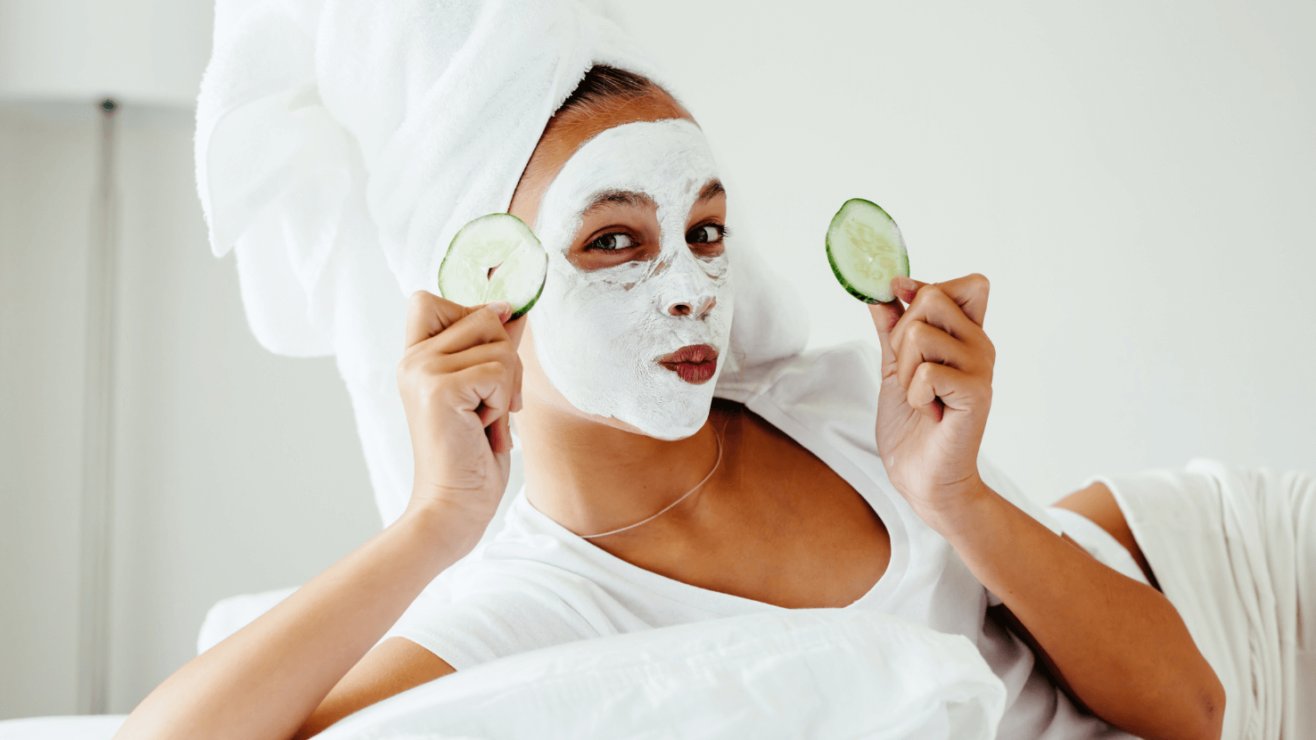 A Woman with A Towel Wrapped Around Her Head Is Holding Cucumber Slices 