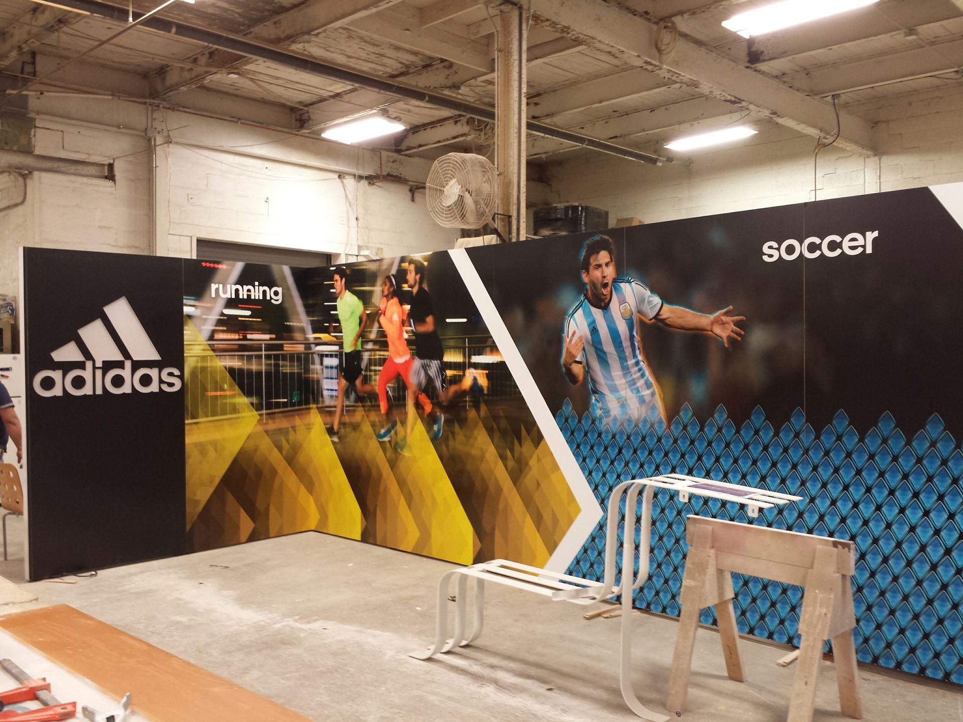 Adidas branded display with soccer player, runners, and text in a warehouse.