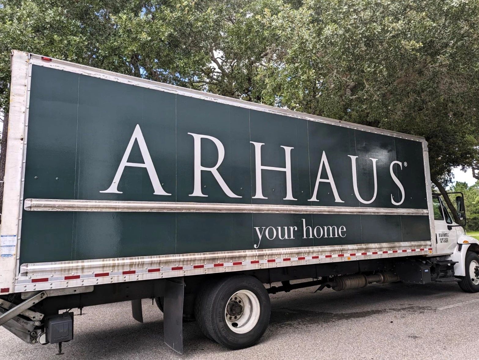 Arhaus delivery truck with dark green and white logo, parked outdoors.