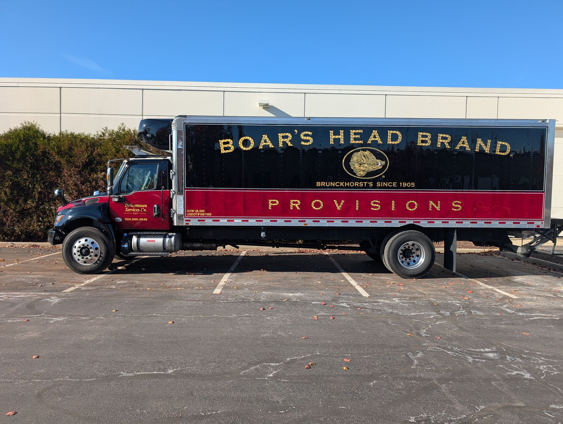 Boar's Head Brand Provisions delivery truck, black and maroon, parked in a lot.