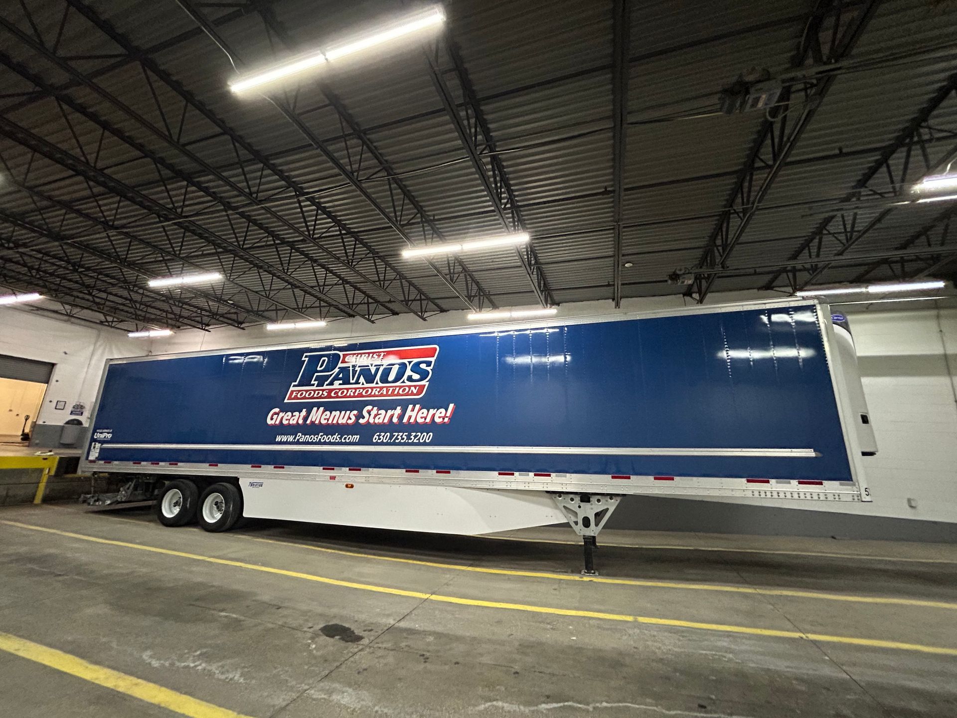 Blue and white semi-trailer inside a warehouse. Trailer has 
