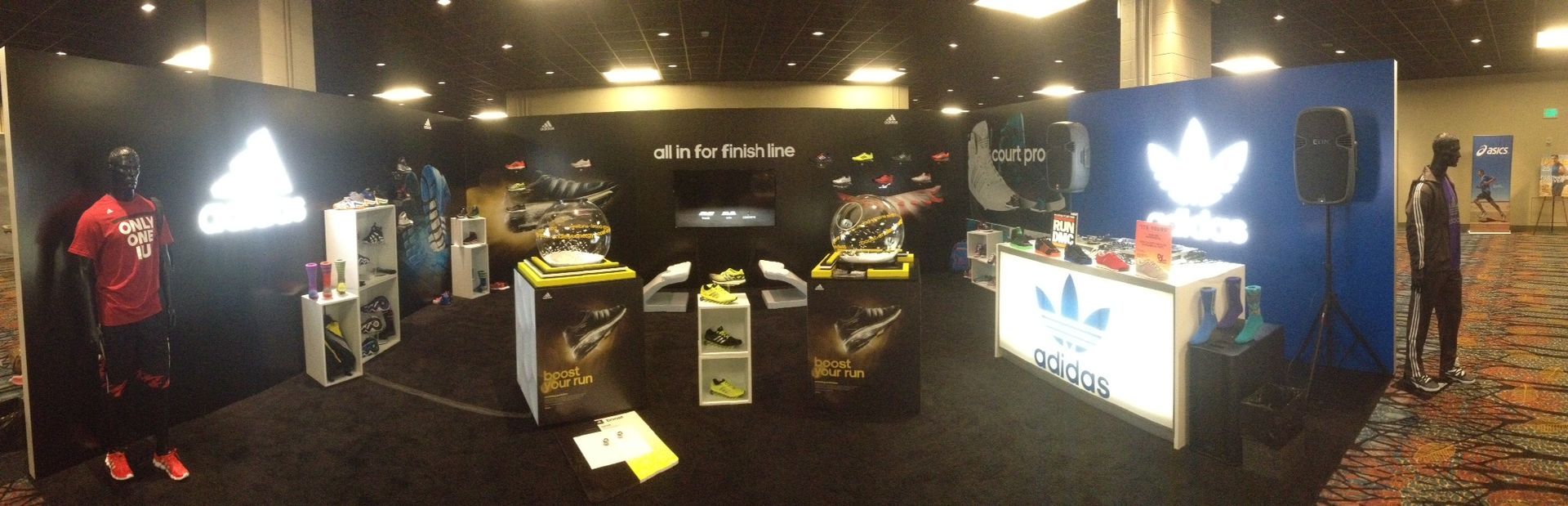 Adidas display at a conference, featuring shoes, mannequins, and illuminated logos.