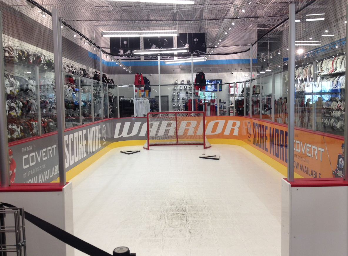 Indoor ice rink with hockey net and equipment displayed on walls.