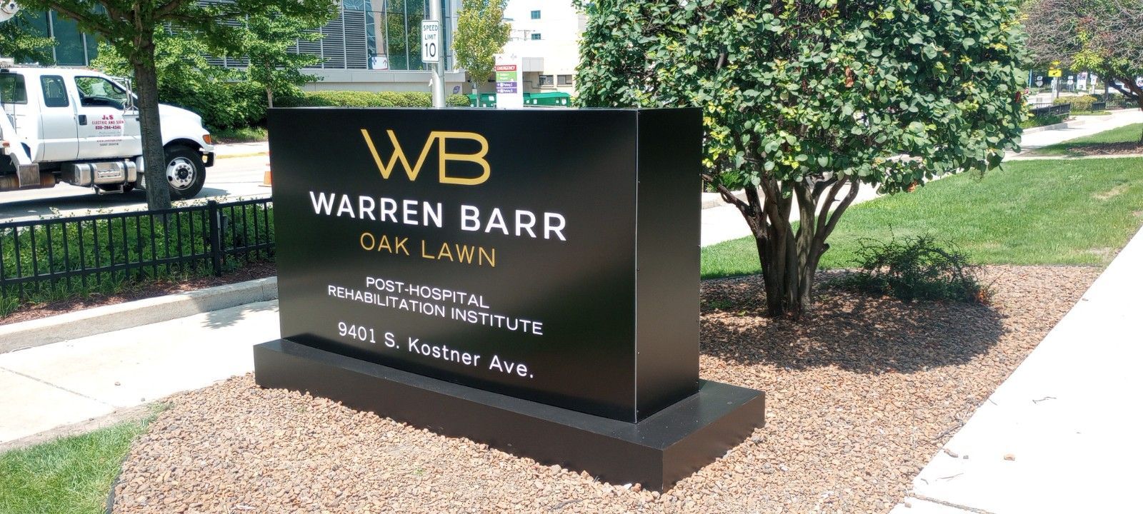 Sign for Warren Barr Oak Lawn with gold lettering on a black background.