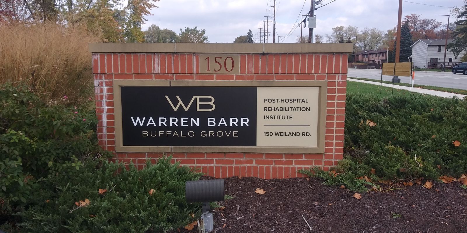 Sign for Warren Barr Buffalo Grove, with address 150. Black sign with gold lettering on brick structure.