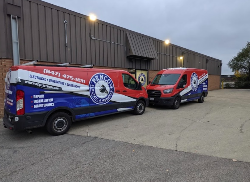 Two red, white, and blue company vans parked in front of a building. The vans have the company's logo and contact information on them.