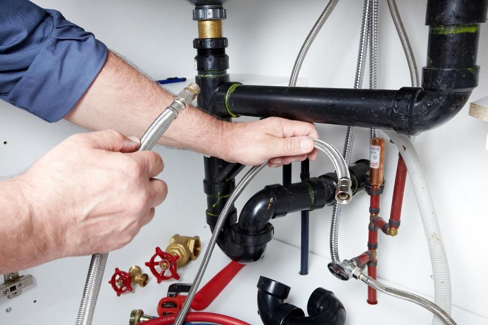 A Plumber Is Fixing A Sink With A Hose — Ashley Chick Plumbing In Baranduda, VIC