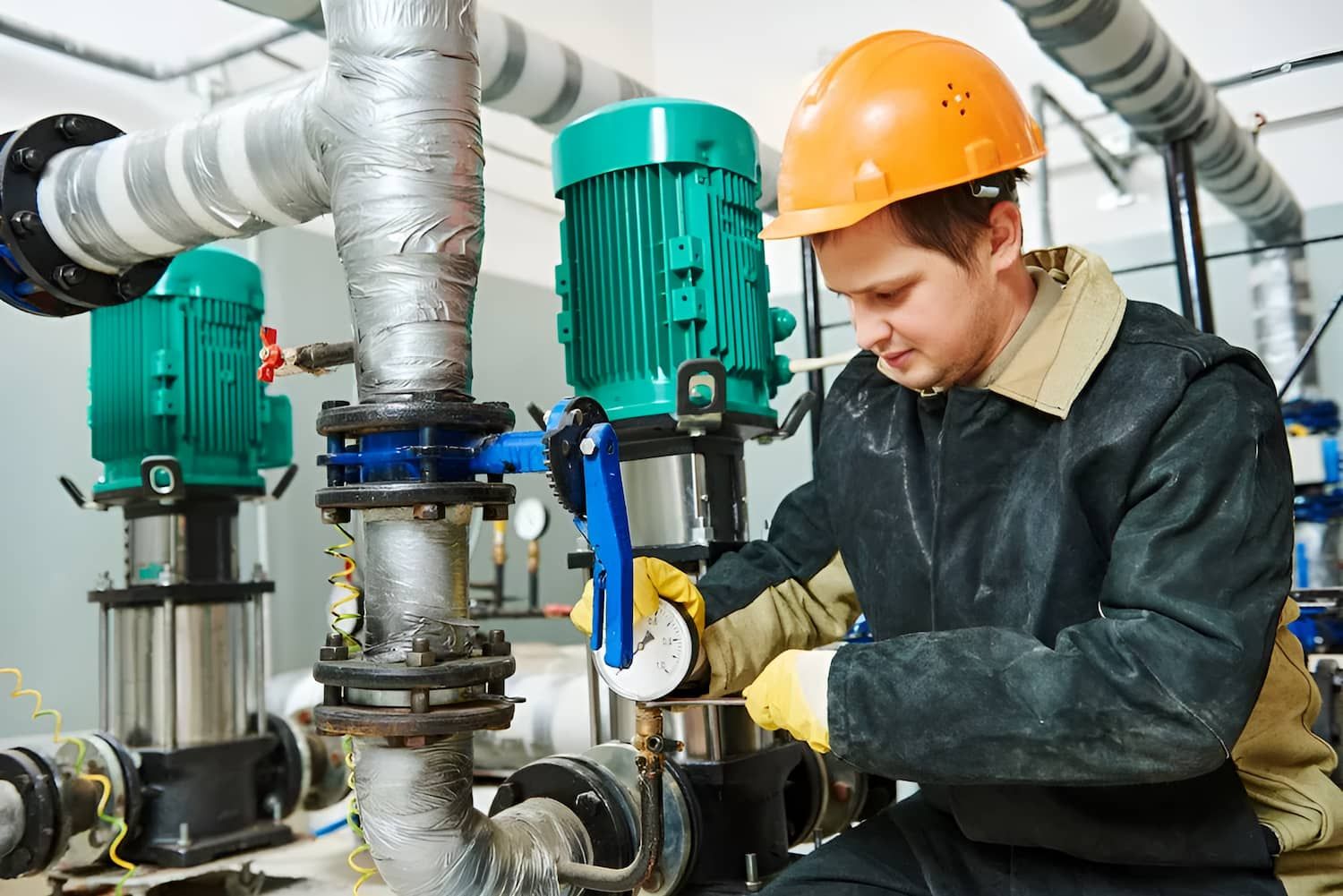 A Man Wearing A Hard Hat Is Working On A Machine In A Factory — Ashley Chick Plumbing In Wodonga, VIC