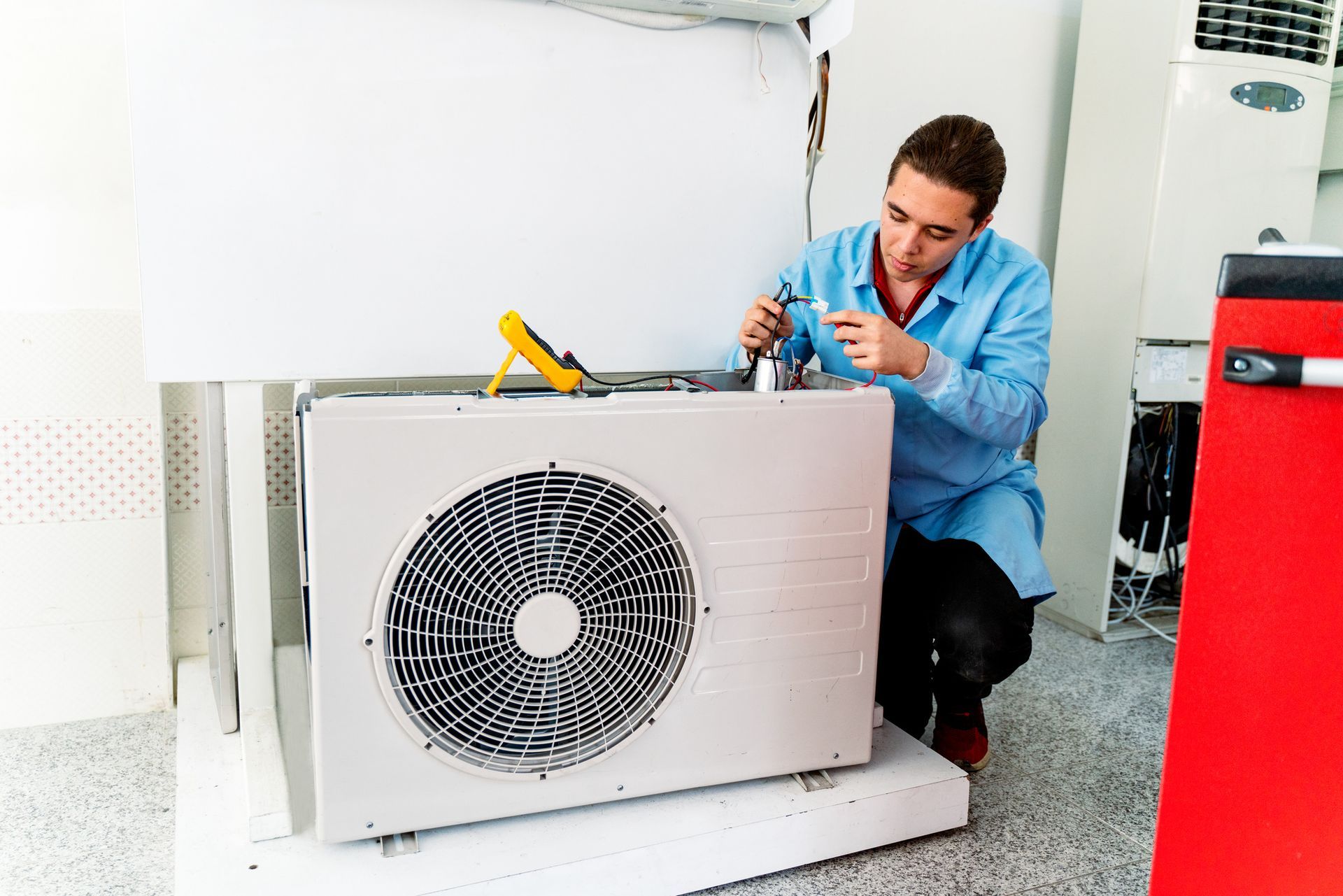 A repairman provides AC repair service as he works on a home unit.