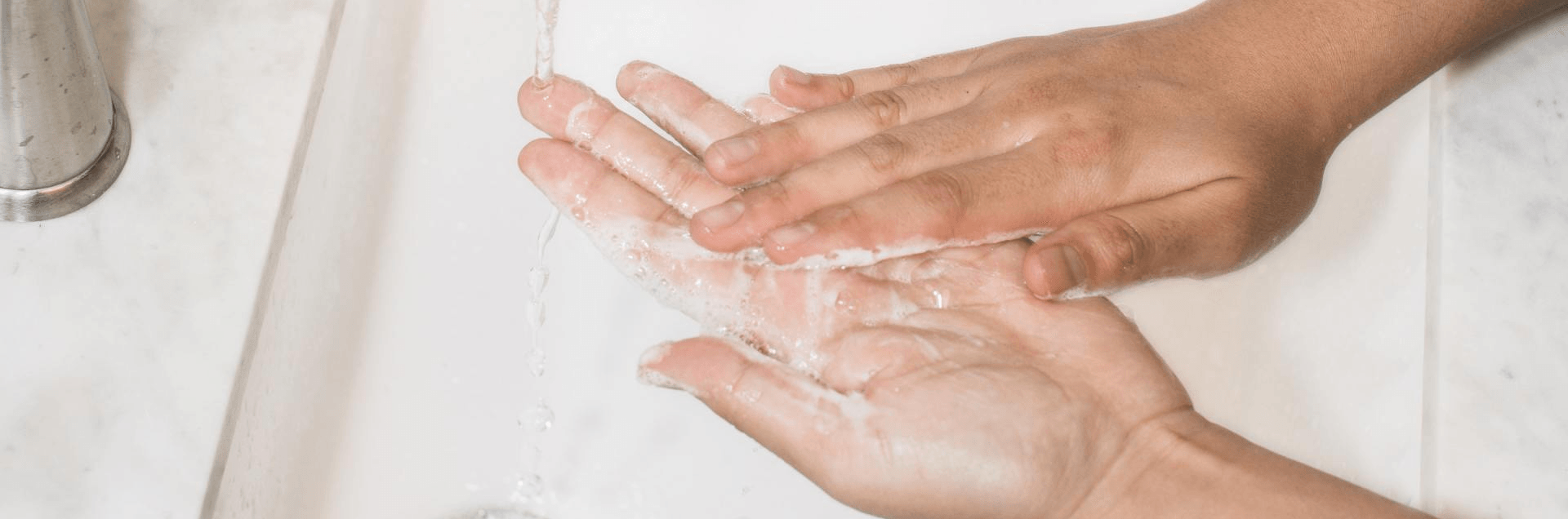 A person is washing their hands with soap under a faucet.