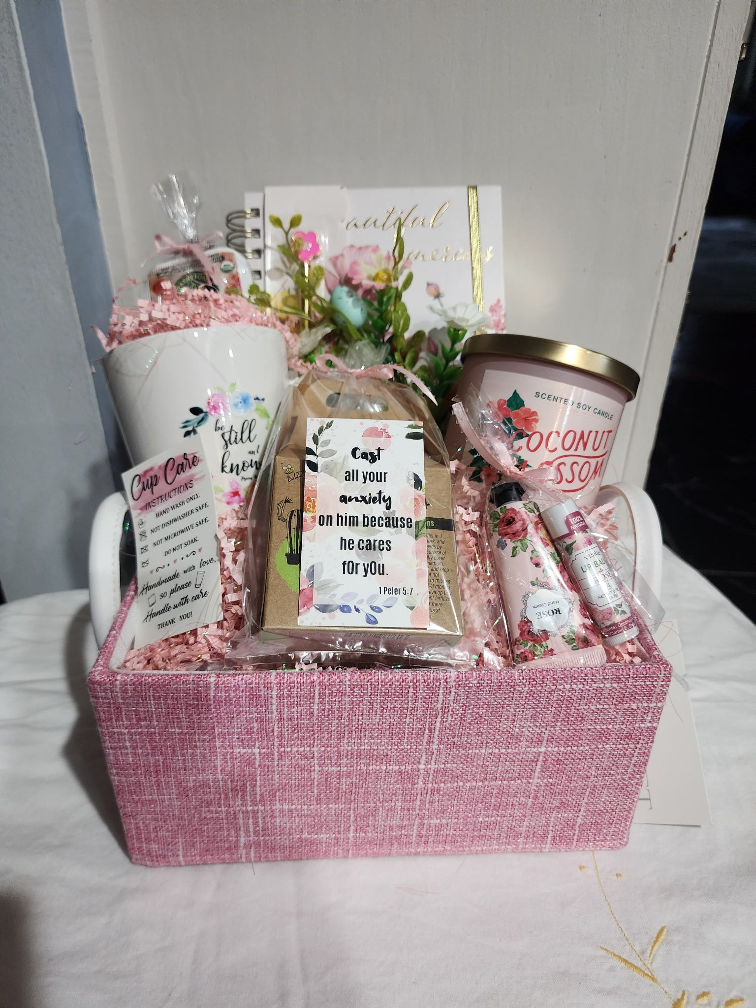Pink gift basket with mug, candle, flowers, and gift card.