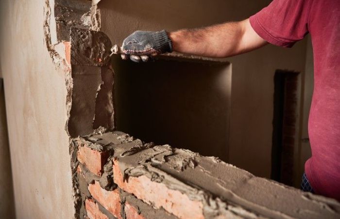 A man with a red shirt installing a brick tile.
