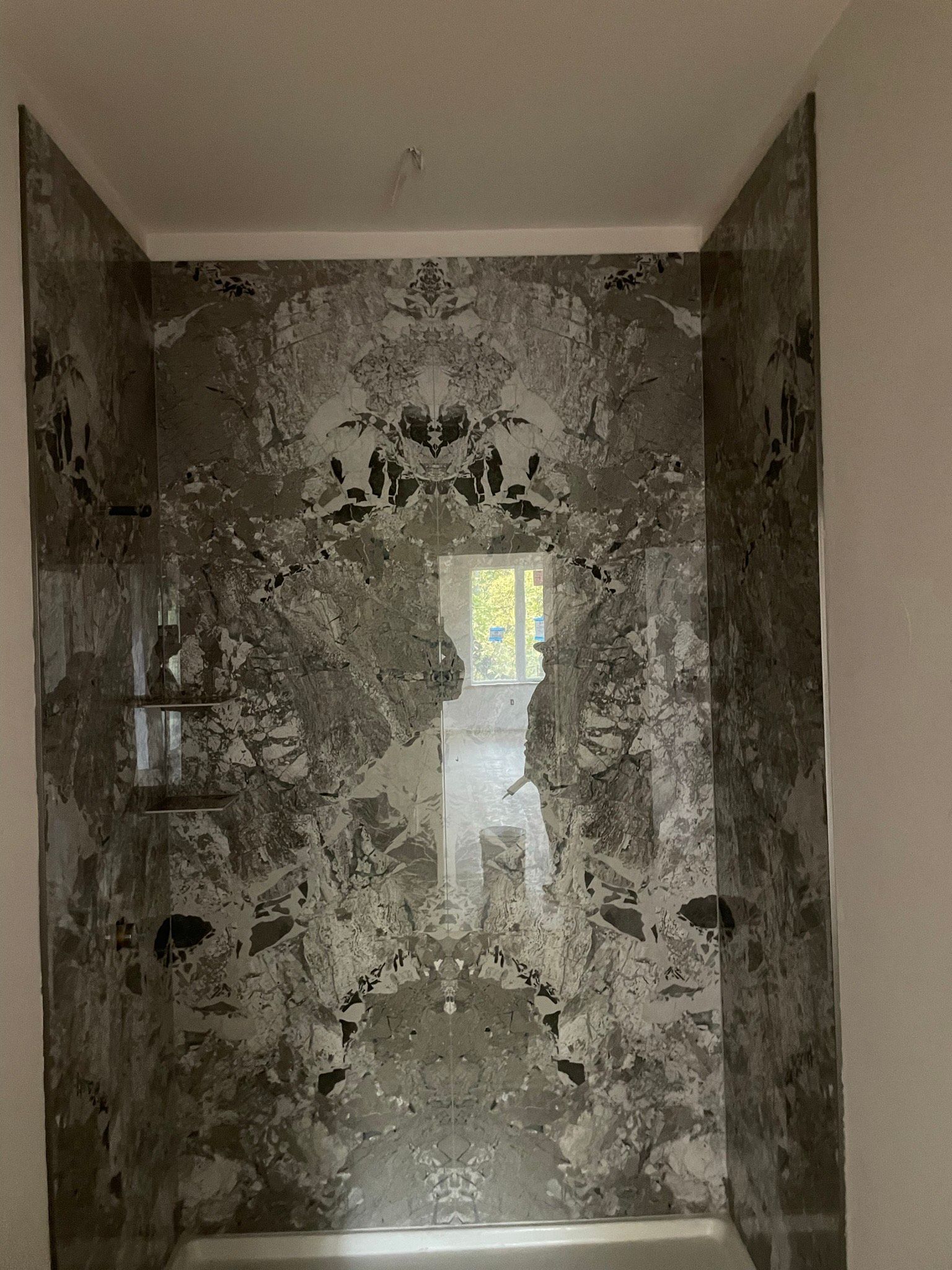 A bathroom with a marble wall and a mirror.