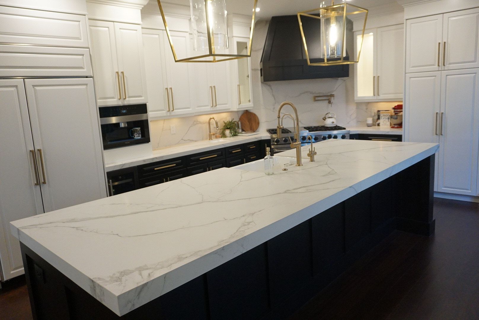 A kitchen with a large island and white counter tops.