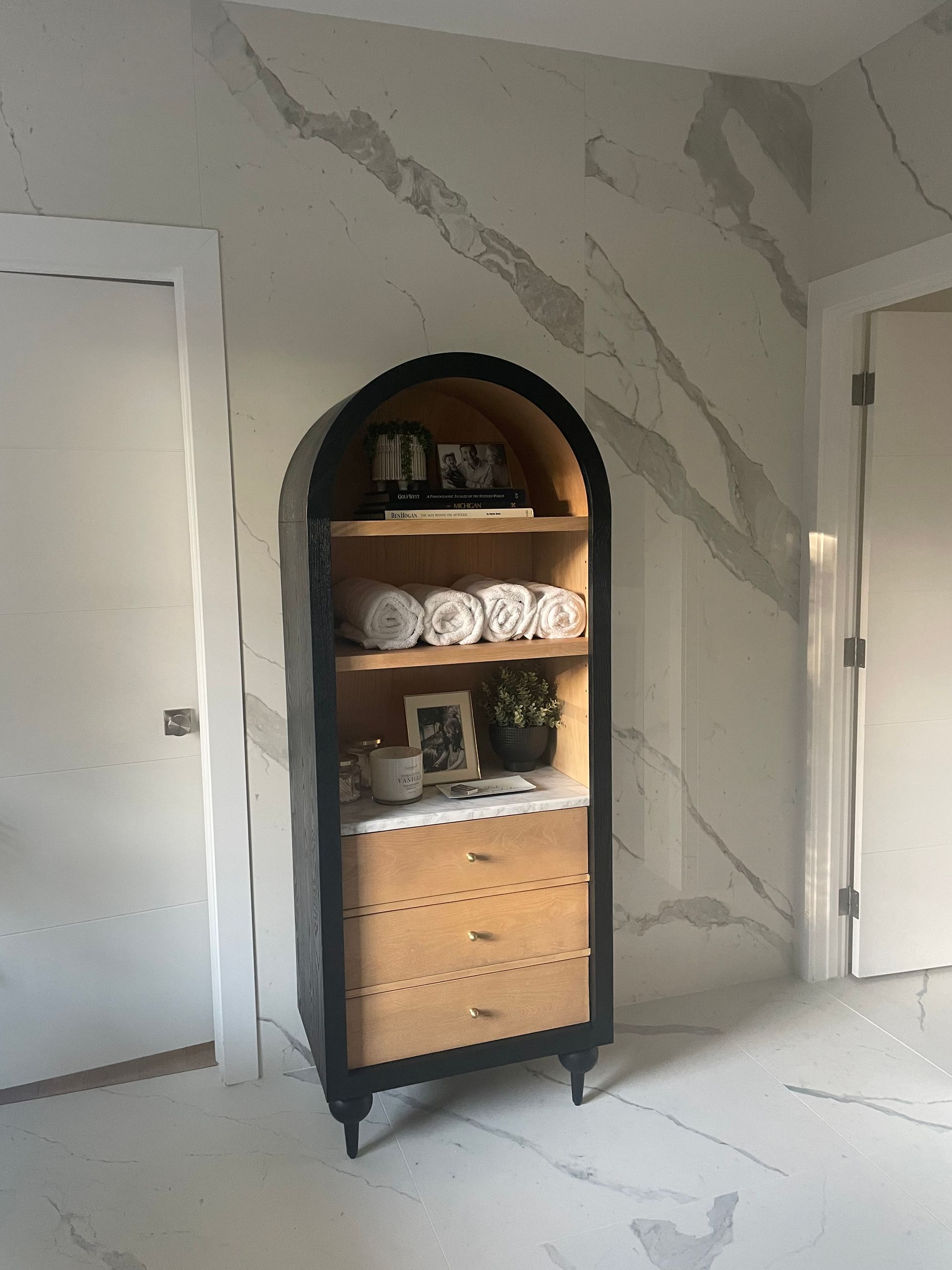 A bathroom with a dresser and a shelf with towels on it.