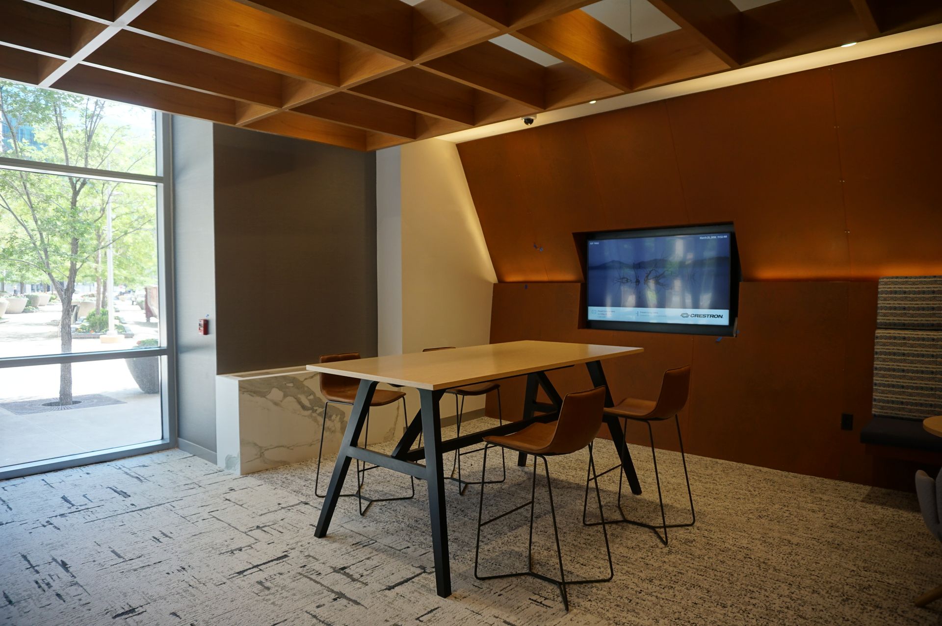 A room with a table and chairs and a television on the wall.