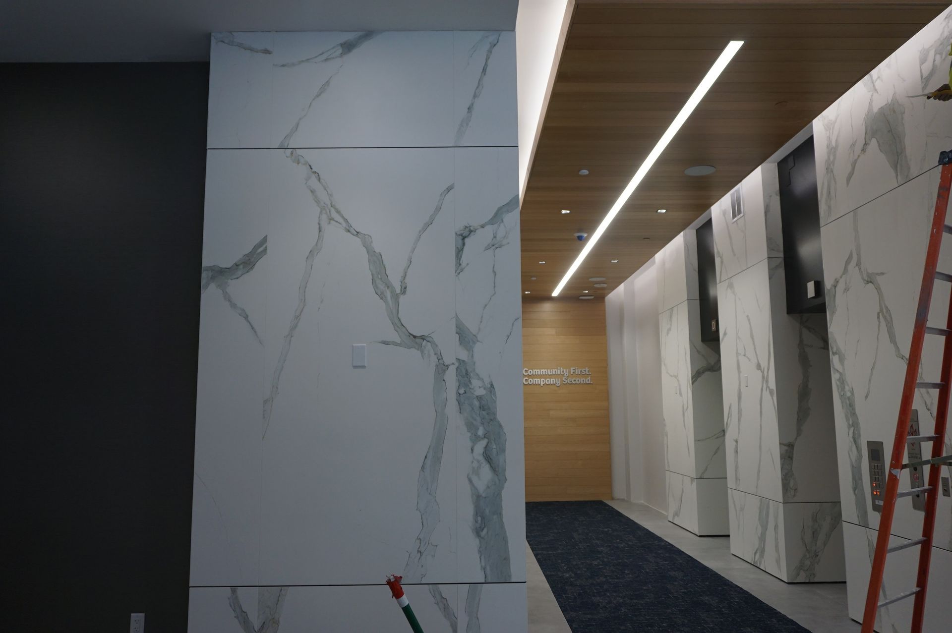 A hallway with marble walls and a ladder in the corner.