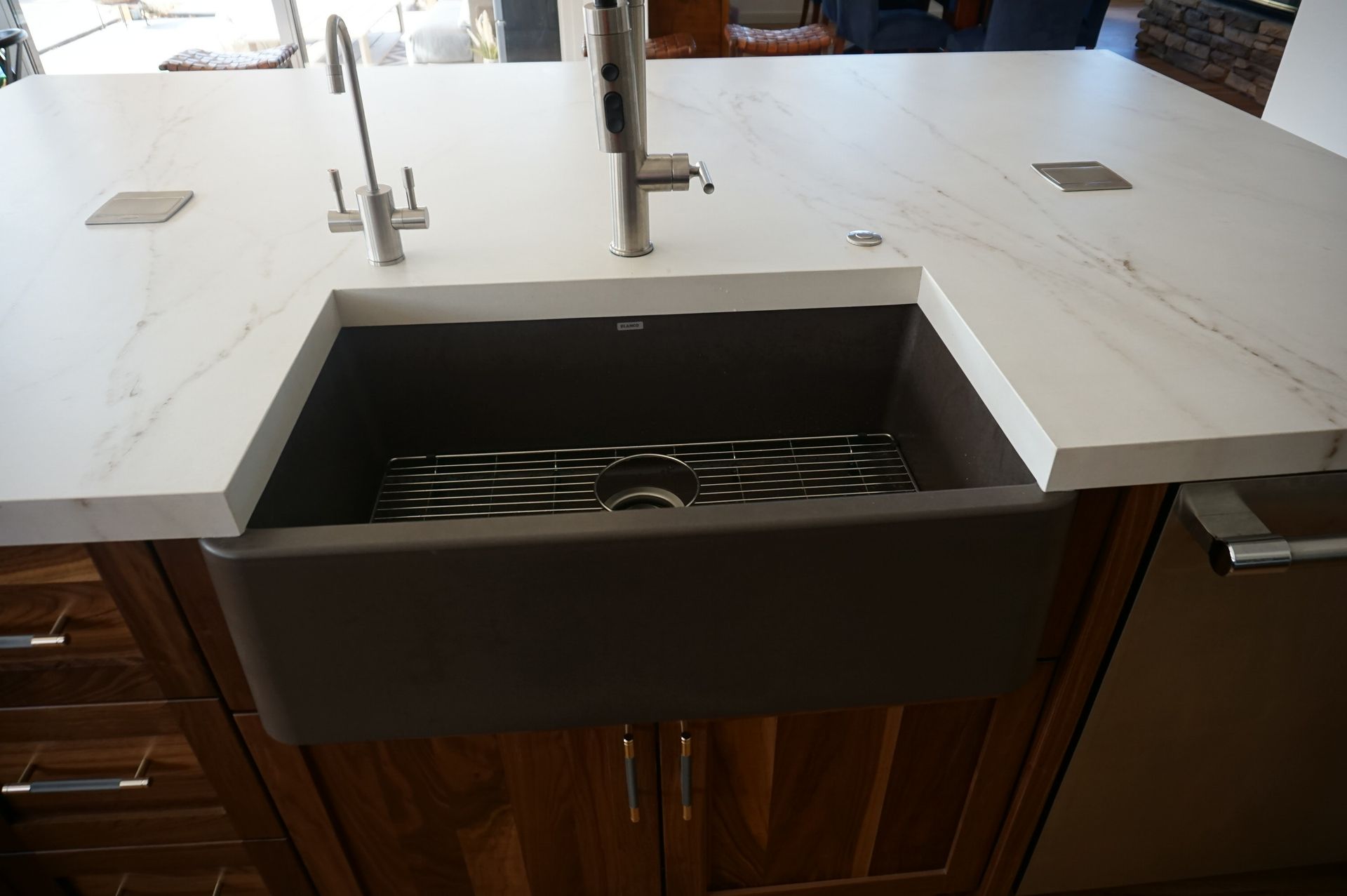 A kitchen sink with a white counter top and wooden cabinets