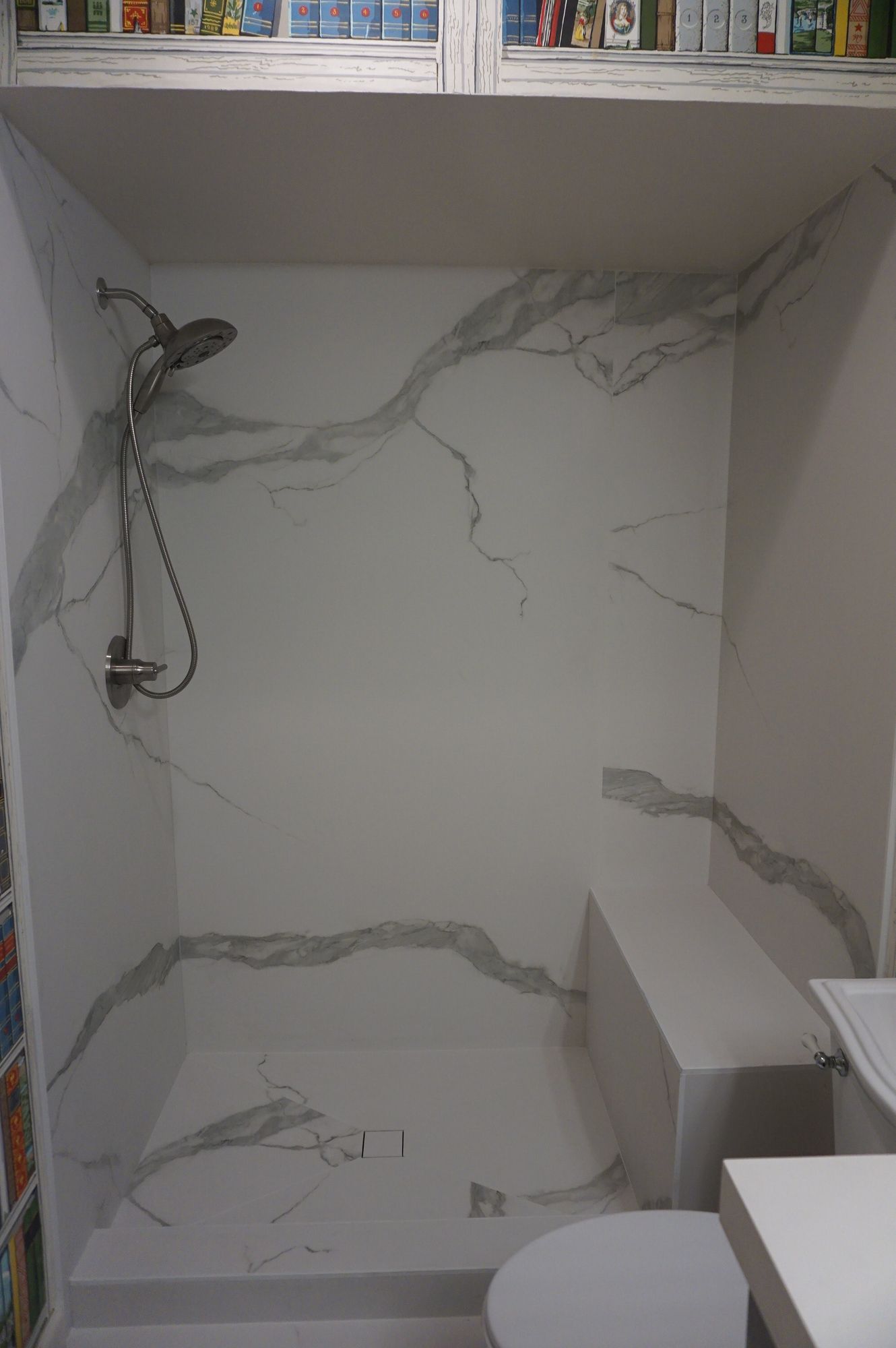 A bathroom with a shower , toilet , and shelf.