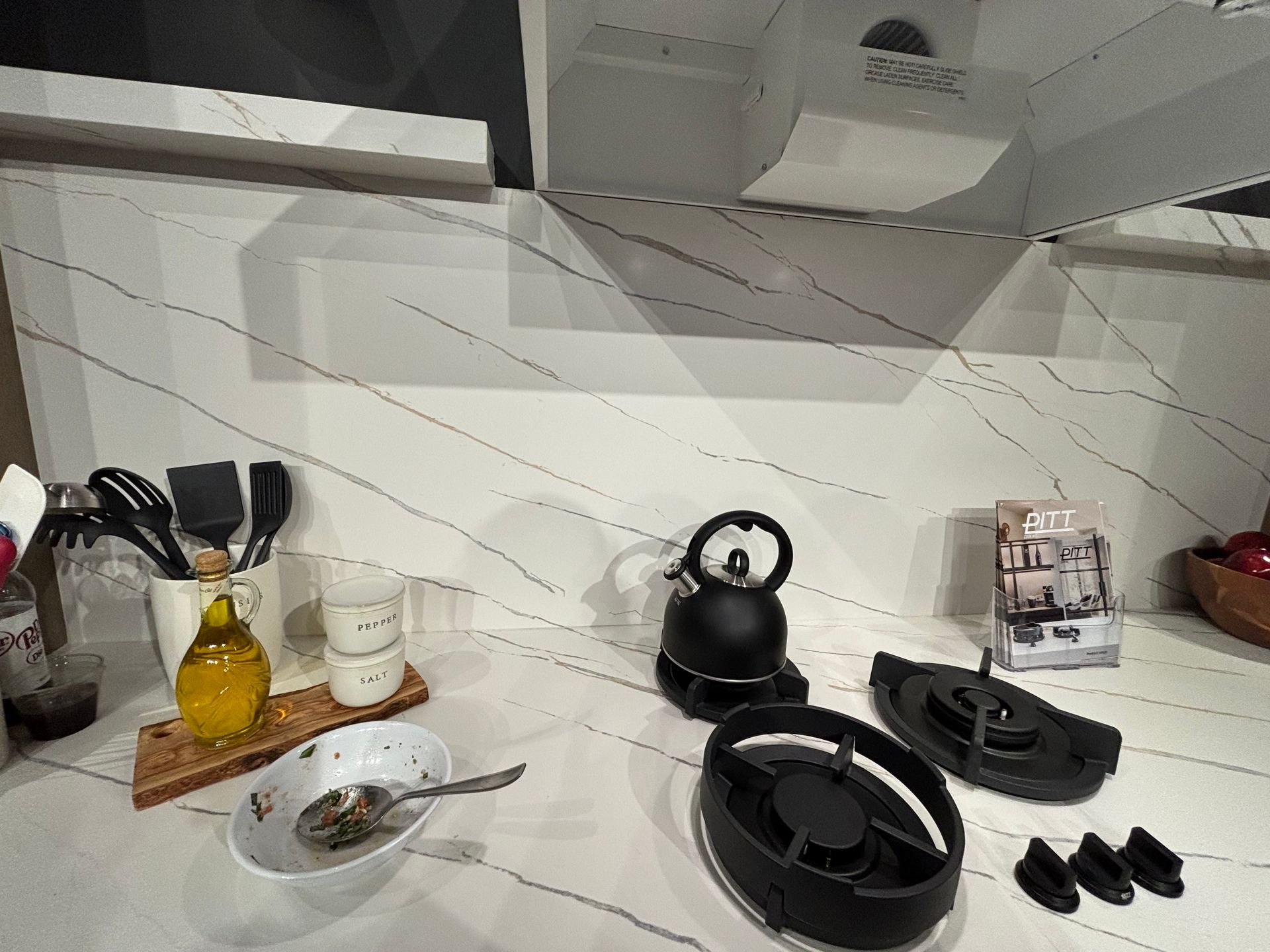 A kitchen counter with utensils , bowls and a kettle on it