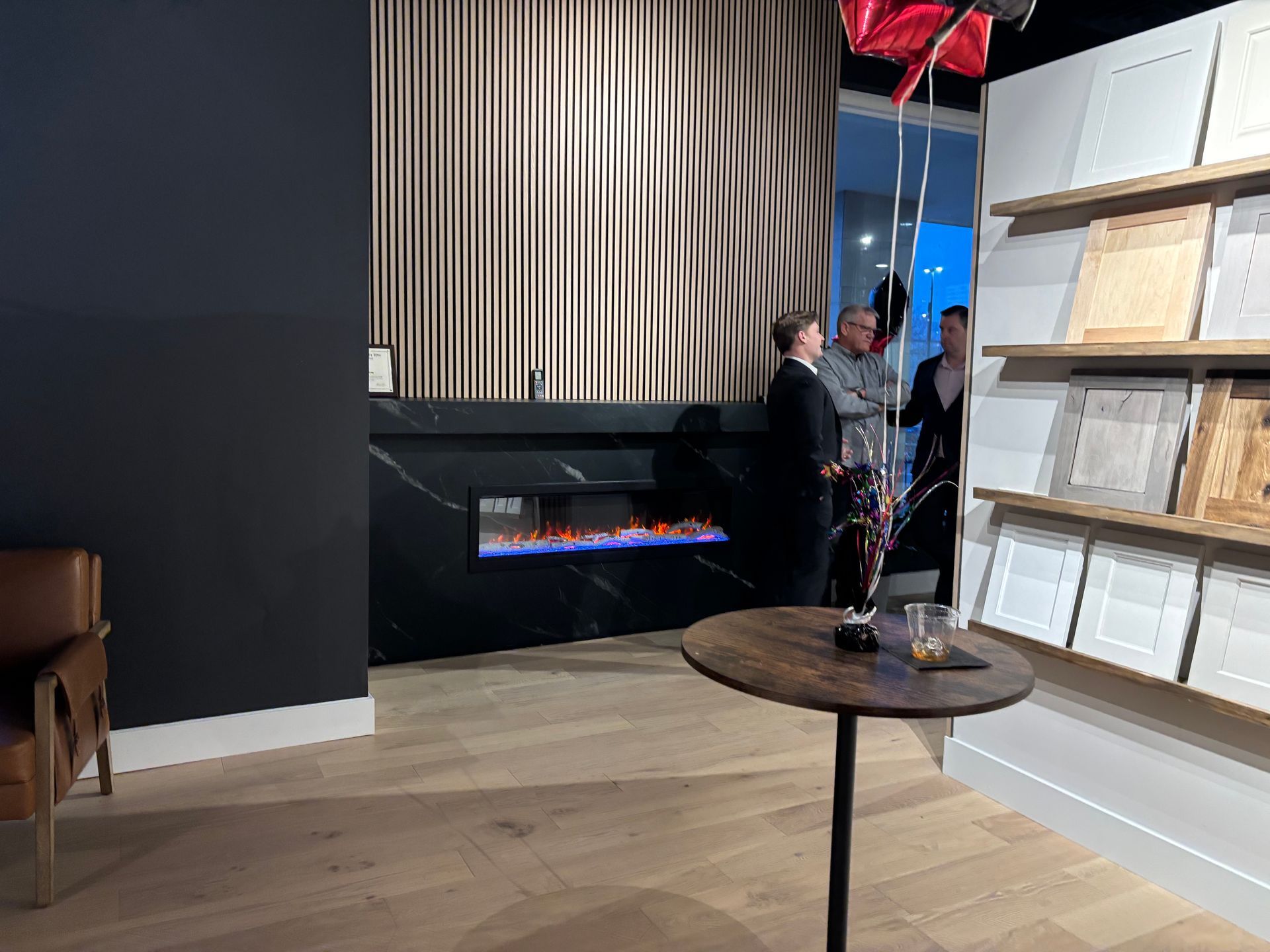 A group of people are standing around a table in a living room.