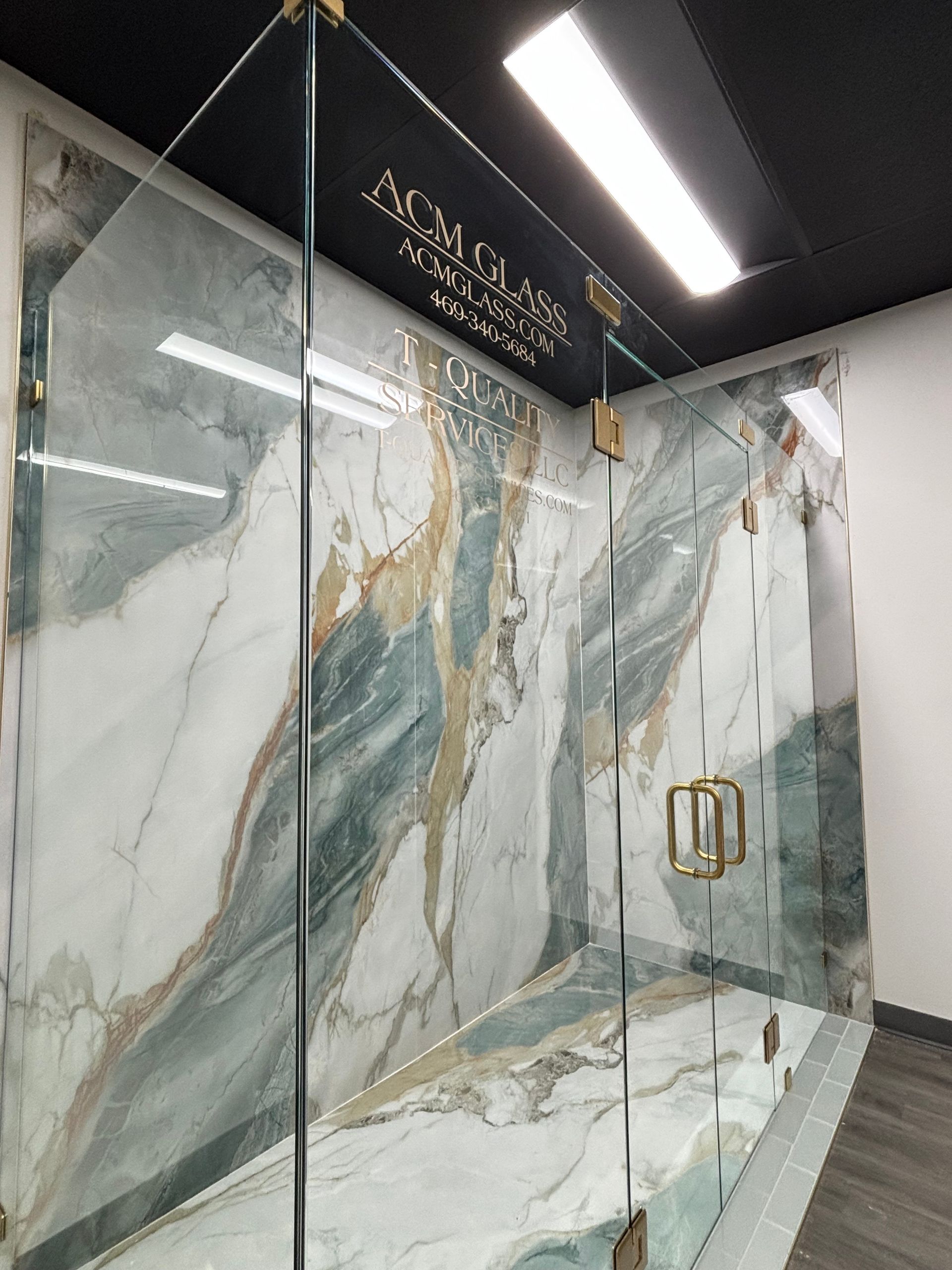 A bathroom with a marble wall and a glass shower door.