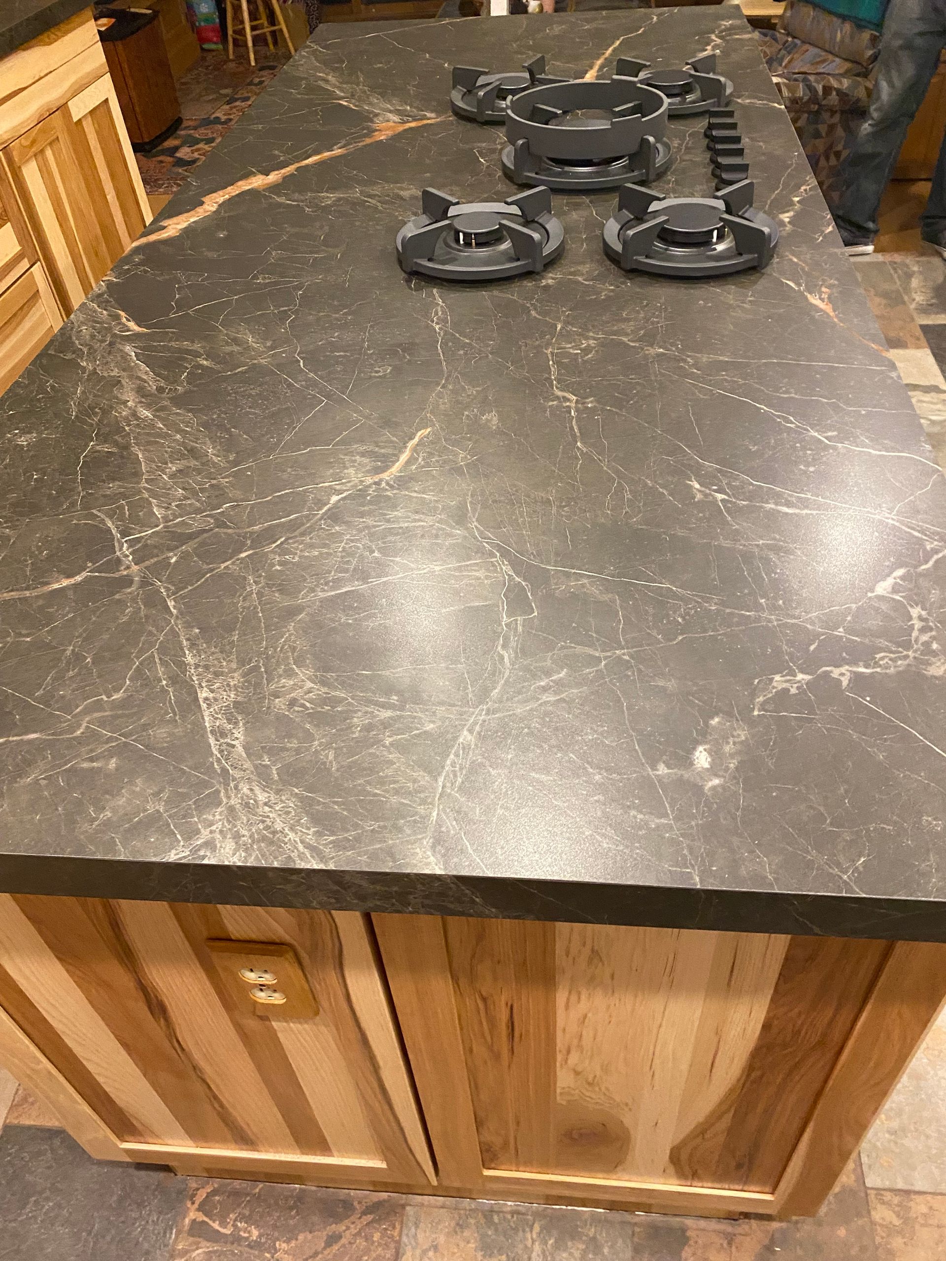 A kitchen island with a stove top oven on top of it.