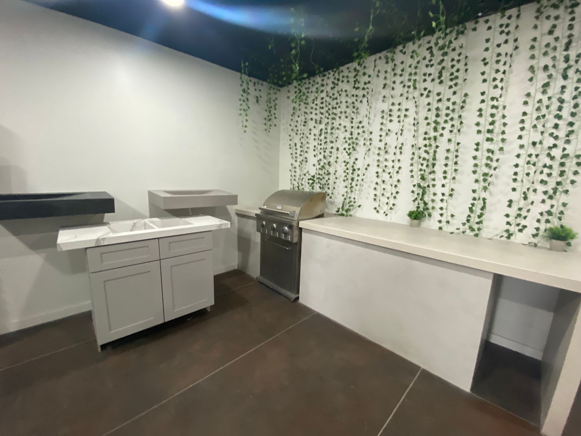 A kitchen with a grill , sink , and cabinets.