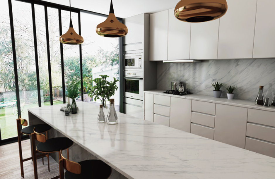 A kitchen with white cabinets , a large island , and a large window.