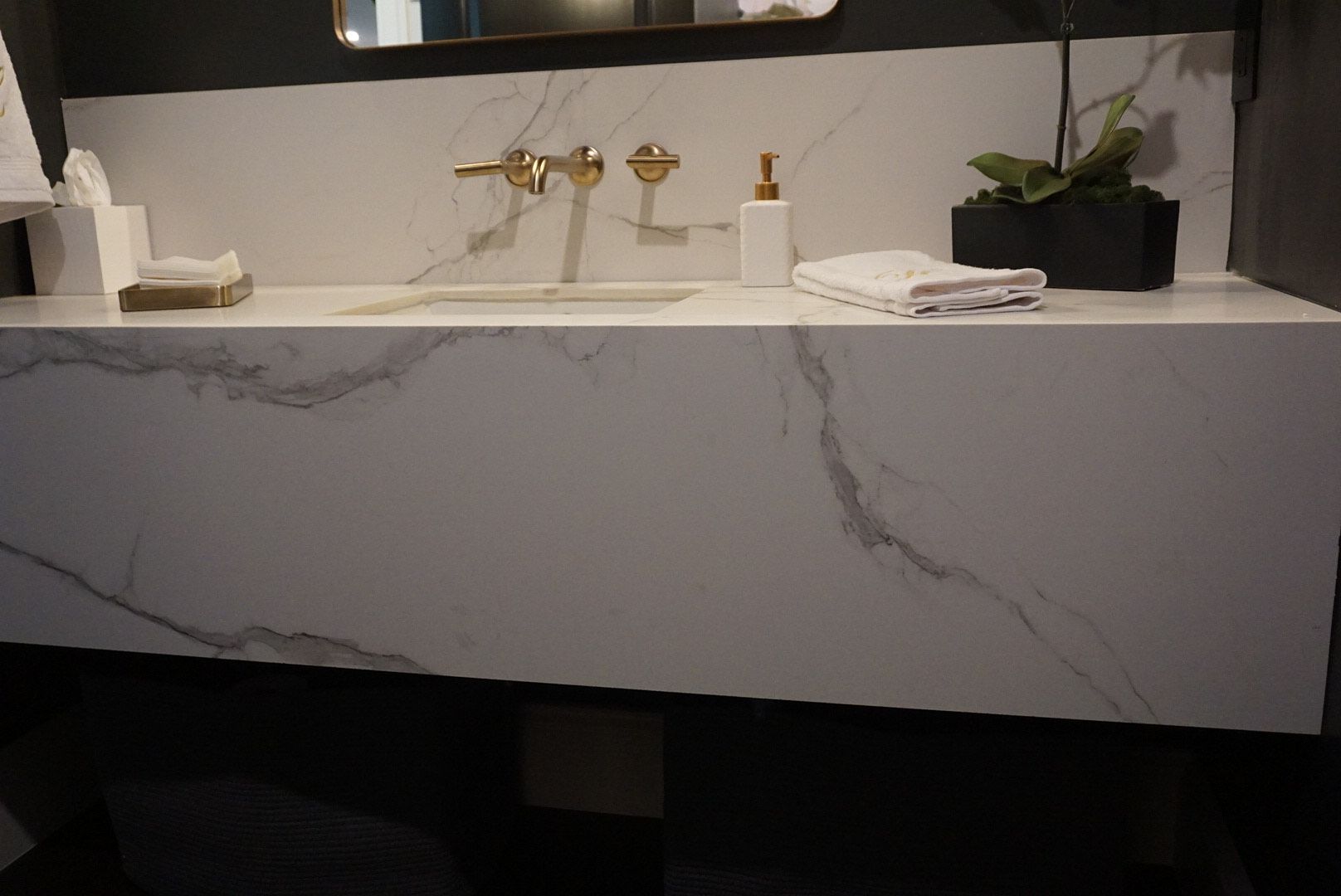 A bathroom sink with a marble counter top and gold faucets
