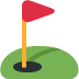 A red flag is sitting on top of a green golf course.