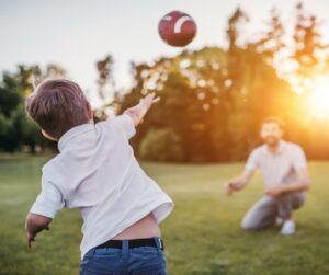 A young boy is throwing a football to his father.