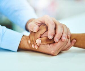 A man is holding a woman 's hand while sitting at a table.