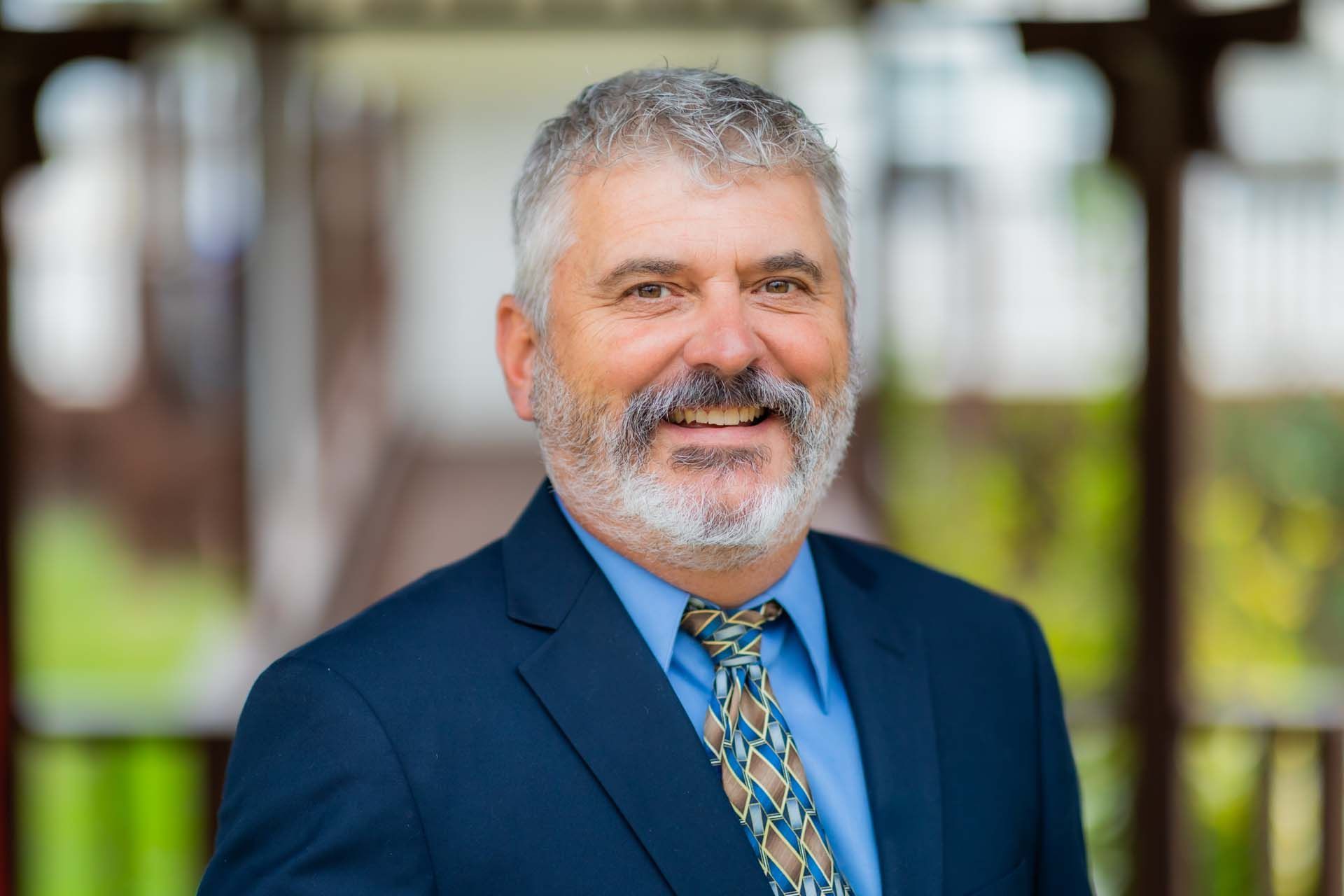 A man in a suit and tie is smiling for the camera.