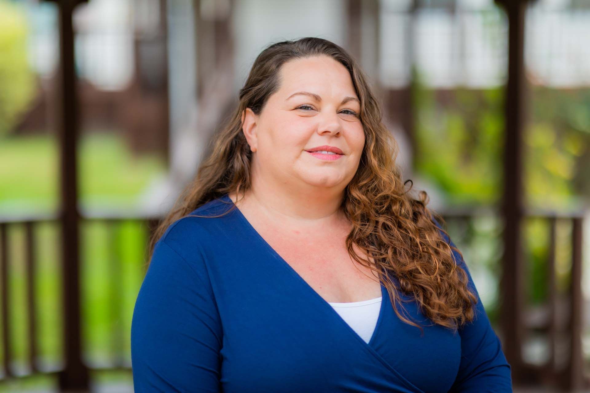 A woman in a blue sweater is standing in front of a gazebo.