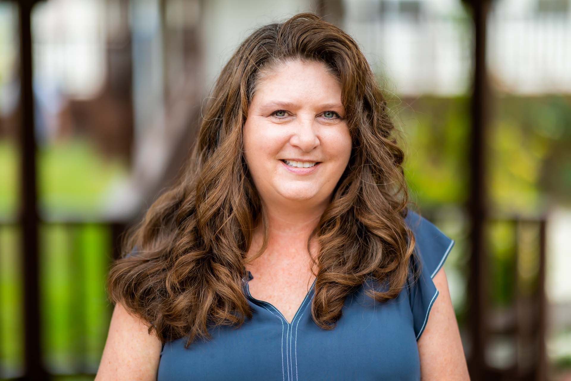 A woman in a blue shirt is smiling for the camera.
