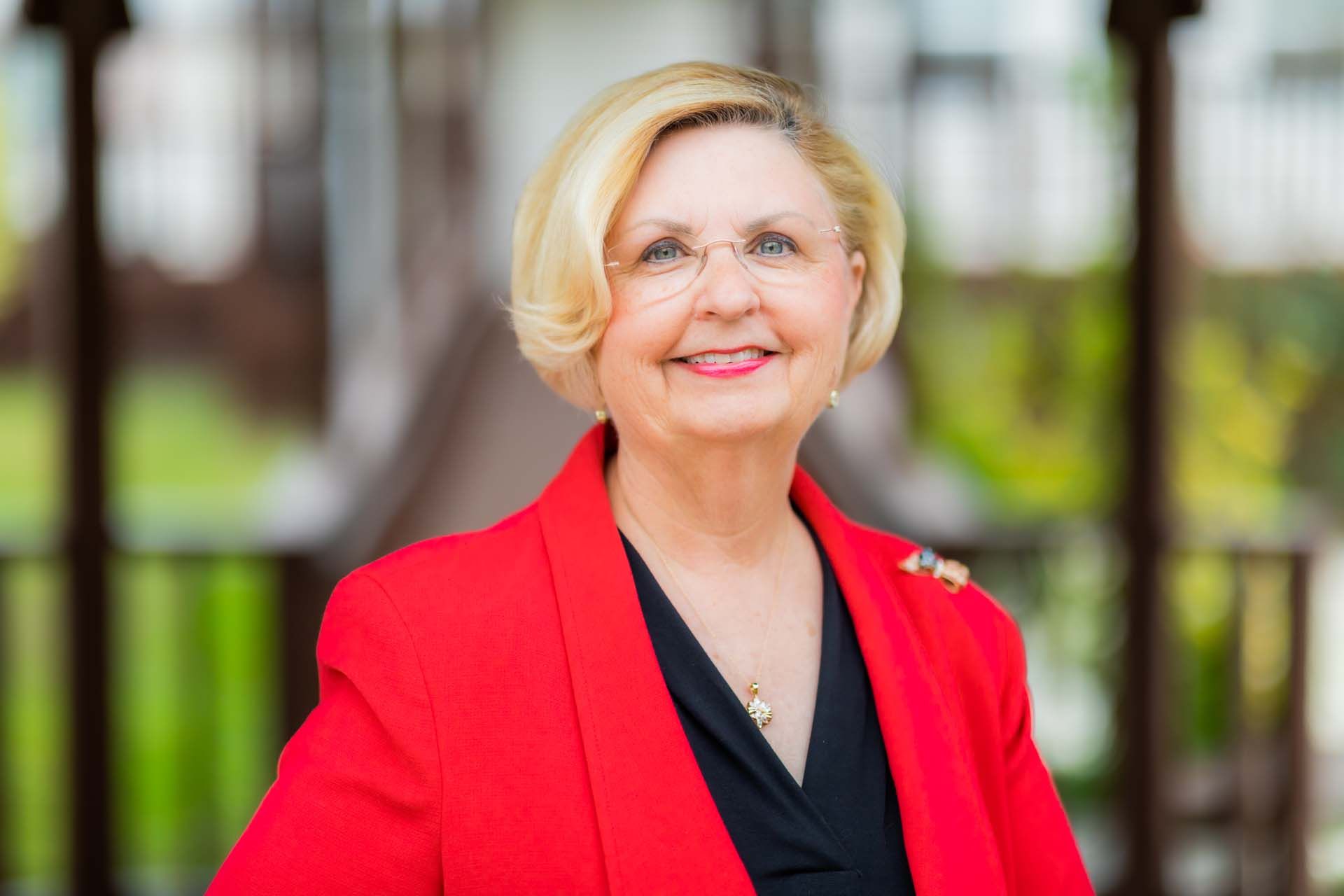 A woman in a red jacket and black shirt is smiling for the camera.